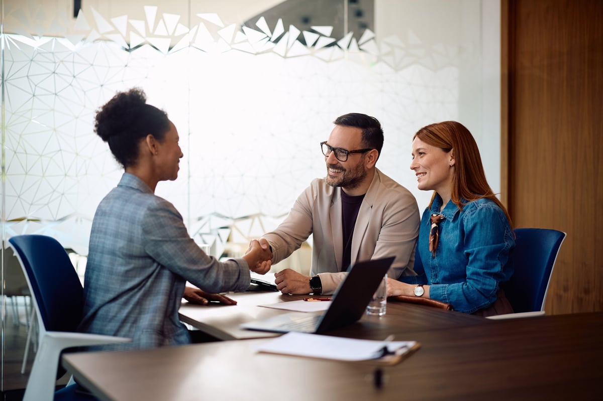 Happy clients shaking hands with their financial advisor